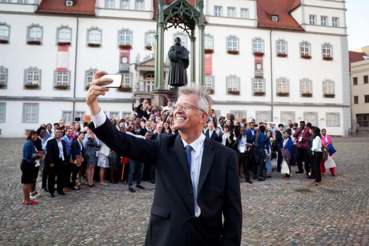 LWF General Secretary Martin Junge taking a selfie of himself, the old reformer Martin Luther and the young reformers on a square in Wittenberg. Photo: LWF/Marko Schoeneberg LWF General Secretary Rev Dr Martin Junge posing with young reformers and a statue of Martin Luther in Wittenberg, Germany